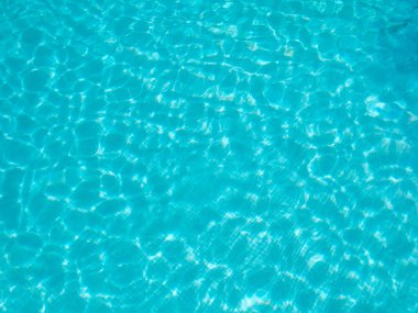 Turkuaz su gün ışığında parlıyor açık havuzda dalgalı bir şablon oluşturuyor. Yaz arkaplanı.