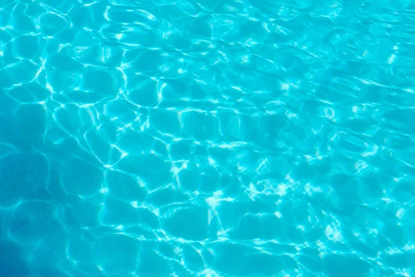 Parlak turkuaz su gösterilir. Güneş ışığı tatil sırasında yüzme havuzunun yüzeyinde desenler ve dalgalanmalar yaratır..