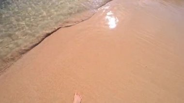 PORTOCOLOM, MALLORCA, İSPA - 25 EKİM 2025: Akdeniz 'den gelen hafif dalgalar kumlu sahile vururken insan sadece ayakları çerçevede yürüyor. Ağır çekim için kullanılabilir.