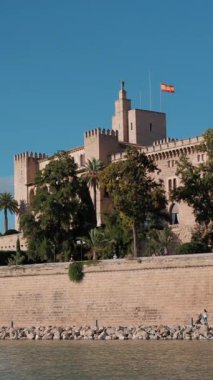 Palma de Mallorca 'da Kraliyet Sarayı Almudaina ve Büyük Katedral sergileniyor. İspanya 'nın açık ve güneşli bir gününde insanlar rıhtım boyunca yürür. Çekim.