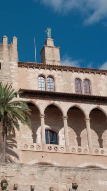 İspanya 'nın Palma de Mallorca şehrinde Almudaina Kraliyet Sarayı parlak mavi bir gökyüzünün altında duruyor. Açık bir günde palmiye ağaçlarıyla tarihi mimari.