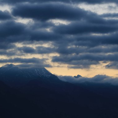 Sunrise scene seen from Boenigen, Interlaken. Dark clouds and bright lit sky over mountain peaks in Switzerland.