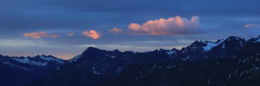 Sunrise scene in the Bernese Oberland. Bright lit cloud over dark mountains.