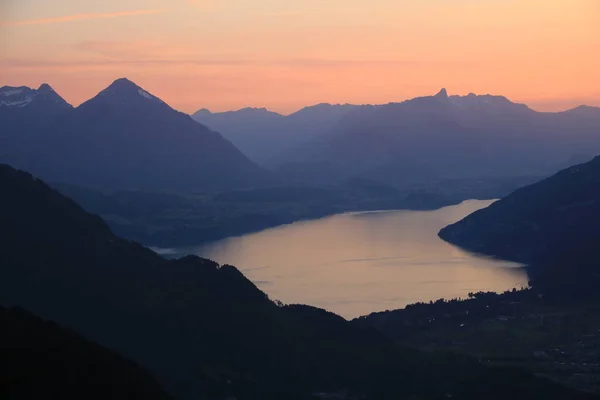 Red evening sky over Lake Thun and mountain ranges in Switzerland.