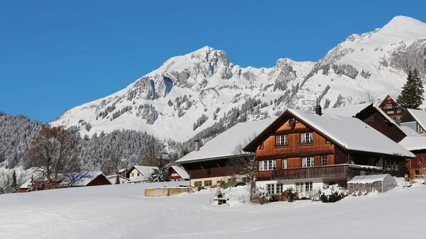 Casa rural en los Alpes suizos y montañas cubiertas de nieve — Foto de Stock