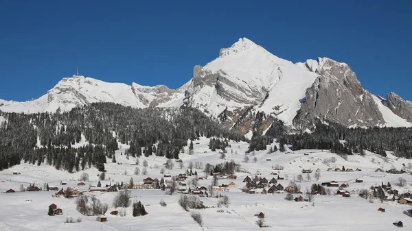 Snön täckte Alpstein utbud och husen i byn Wildhaus — Stockfoto