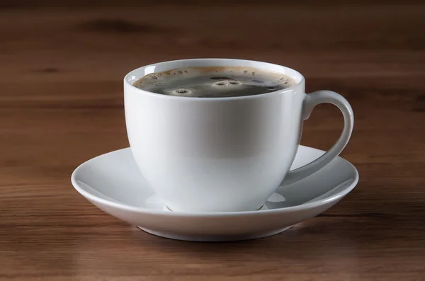 Koffiekopje en bonen op houten textuur — Stockfoto