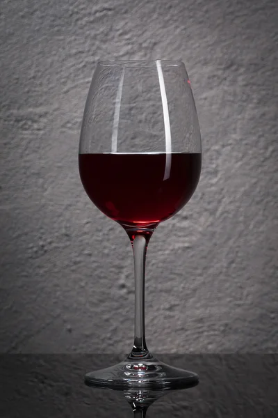 Il vetro. Bicchiere di vino rosso davanti al muro di granito di pietra — Foto Stock