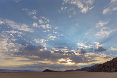 Namib Çölü 'nde sabah bulutların arasından güneş ışınları yayılıyor.