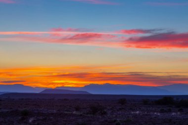 Karoo 'da gün batımında turuncu bulutlar ve mavi dağlar
