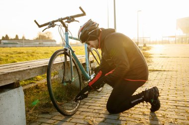 Bir adam bisikletinin ön tekerleğini şişirir.