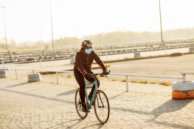 Karantina sırasında bisikletçi maske takıp bisiklet sürüyor.