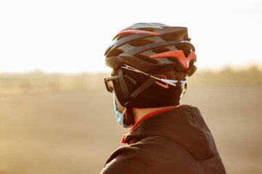 Kask ve maskeyle karantina sırasında bisikletçi.