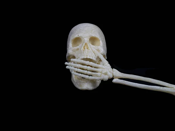 Human skull covers its mouth with a skeleton hand, cannot speak, sign of silence or violence — Stockfoto