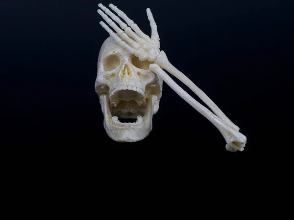 Un crâne humain avec une bouche ouverte ressemblant à un rire couvre ses yeux d'une main squelette, visage de la main — Photo