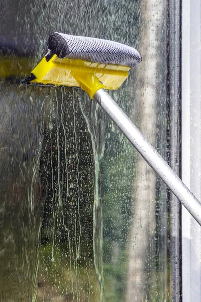 washing Windows, cleaning glasses and surfaces. yellow-white telescopic washing brush cleanly washes and wipes the Windows of the house.