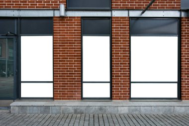 Bir alışveriş merkezinin vitrinindeki reklam panolarına karşı kırmızı tuğladan bir duvar. Mal ve mağazalarınız için cep telefonu reklamları.