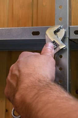 Metal raflar, el emeği, ingiliz anahtarı kullanımı, mekanik montajlar ya da rafları sökmek. Eller çerçevede, dikiz aynasından.