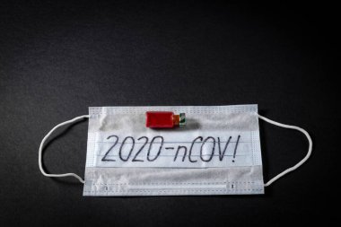 Korunaklı bir maskenin arka planına karşı hızla yayılan yeni bir koronavirüs için yapılan kan testinin sonucuyla dolu bir şırınga. NCOV-2020 salgını Çin 'in Wuhan şehrinden geliyor.