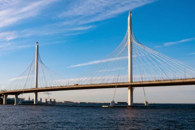 Mavi gökyüzü ve mavi denizin arka planında kablo destekli büyük ve güzel bir köprü..