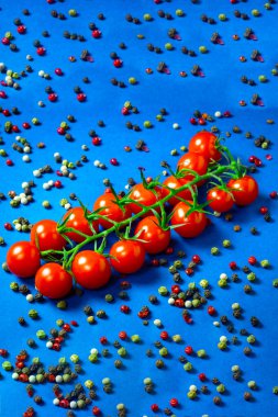 Yemek geçmişi. Bir dalda taze kırmızı kiraz domatesi ya da renkli mavi arka planda farklı çeşitlerde biberli tatlı bir kız.