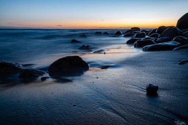 Denizin üzerinde çok güzel bir gün batımı klasik mavi bir renkle, seçici bir odak noktasıyla resmedilir.