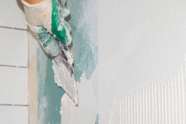 Usta macunu bir spatula kullanarak giprok duvarına sürme işlemi. onarım çalışmaları ve döşeme döşemeleri.
