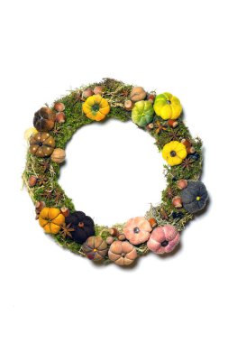 Beyaz arka planda izole edilmiş Noel çelengi, küçük el yapımı balkabakları, doğal fındık, yosun, kakule.