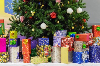 Noel ve yeni yıl tatillerinde, çok sayıda hediye çok renkli bir ambalaj kağıdıyla ağaçta güzel oyuncaklarla büyük bir Noel ağacının altında..