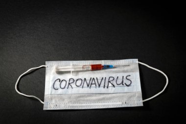 Korunaklı bir maskenin arka planına karşı hızla yayılan yeni bir koronavirüs için yapılan kan testinin sonucuyla dolu bir şırınga. NCOV-2020 salgını Çin 'in Wuhan şehrinden geliyor.