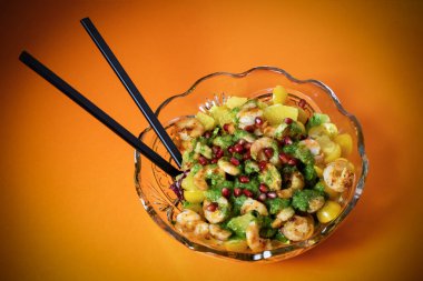 Kırmızı zemin üzerinde lezzetli ve sağlıklı yiyecekler, taze meyve, portakal, mango, avokado, sarı kiraz, nar, marul ve karides salatası. sağlıklı diyet yemekleri.