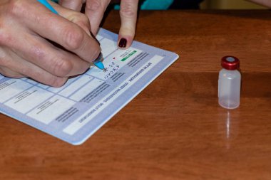 Doktor yeni bir aşıyı, bir şişe panzehiri, ilacı, ilacı test ettikten sonra belgeleri doldurur..