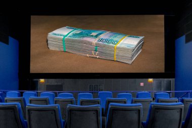 Koronavirüs salgını sırasında boş bir sinema salonunda gri arka planda bir paket Rus rublesi gösterilir. Ulusal para biriminin dolar karşısında keskin düşüşü
