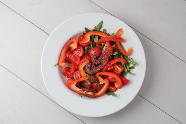 Sulu ve parlak, vejetaryenler için diyet salatası. Beyaz tabakta vitamin açısından zengin sağlıklı yiyecekler tahta beyaz arka planda durur. Yukarıdan görünüm.