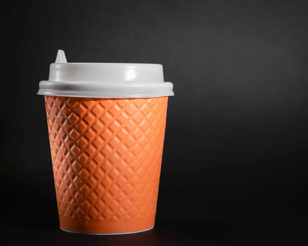 Black background takeaway coffee cup, disposable orange cup