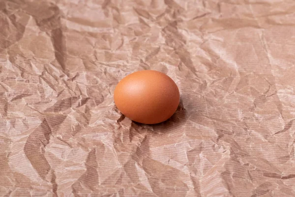 Seitenansicht Eines Braunen Hühnereiers Auf Einem Zerknüllten Papiergrauen Hintergrund — Stockfoto