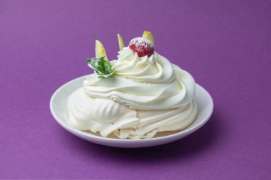 Mor arkaplanda beyaz bir tabakta vişneli ve nane aromalı tek bir krema.