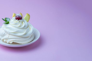 Beyaz tabakta Pavlova kremalı tatlı ve pembe arka plan. Kremalı, yuvarlak kremalı kremalı krema, nane yapraklı ve kirazlı tatlı.