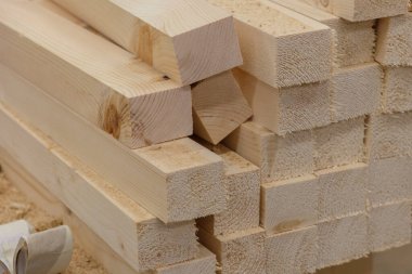 Marangozluk atölyesindeki malzemelerin arkasında aletler ve talaş olan meşe ağacı ahşap bar blokları. Tahta kurusıkı. Kereste ışın detaylarını kapat. El işi hobisi