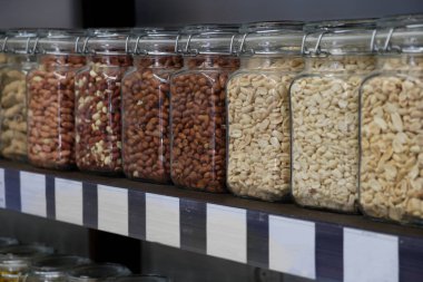 Rafta cam kavanozlarda çeşitli lezzetli kavrulmuş ve soyulmuş fındık çeşitleri var..