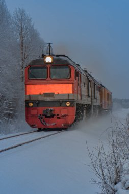 Karlı kış ormanı sahnesi ve St. Petersburg yakınlarında eski renkli bir dizel tren.