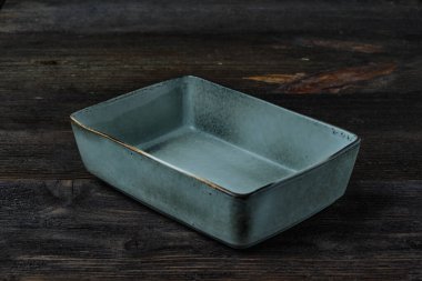 Salatalar ve sıcak yemekler için dikdörtgen boş tabak koyu kahverengi ahşap arka planda pastel renk. Yan görünüm.