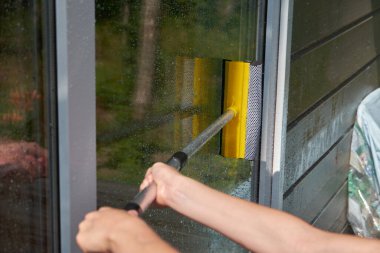 Paspaslı bir el büyük bir pencereyi siler.