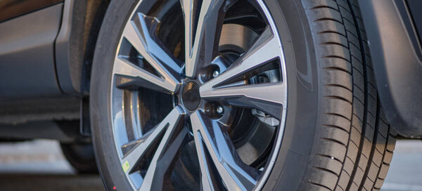 Part of a modern new car with wheel, alloy wheel and disc brake pad on brake disc.