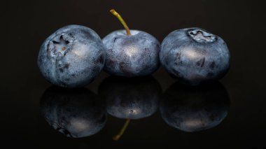 Siyah arka planda yansıması olan taze yabanmersini. Yan görünüm.