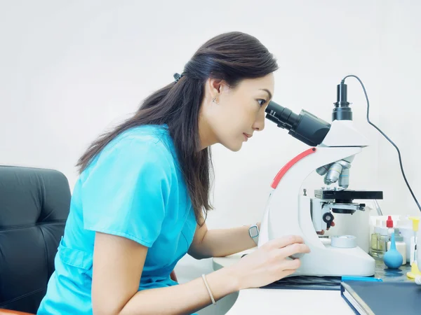 Retrato de mujer joven asiática médico mirando al microscopio en laboratorio — Foto de Stock