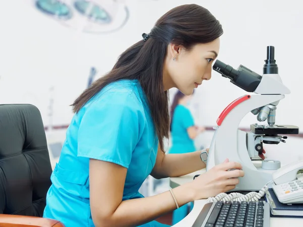 Retrato de jovem asiático mulher médico olhando para microscópio em laboratório — Fotografia de Stock