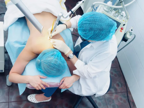 Лазерное лечение. Кавказский врач делает процедуру удаления кожи невуса женщине пациентке Лицензионные Стоковые Изображения