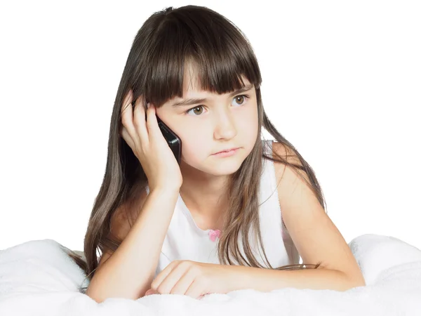 Caucasian child kid girl sister lying on the bed with mobile phone isolated — Stock Photo, Image