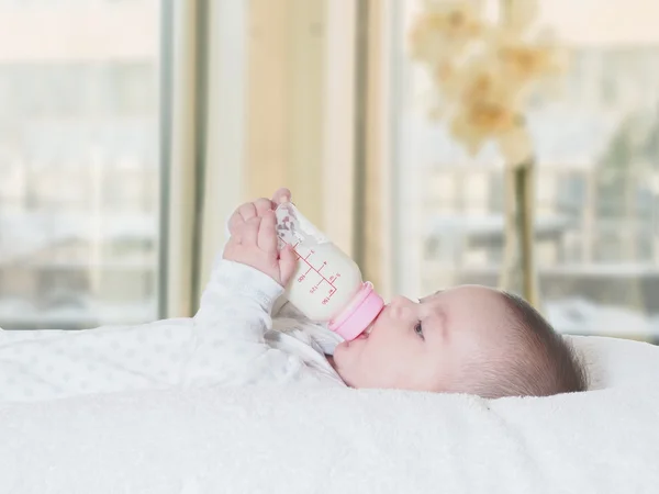 Baby boy  drinking milk from the bottle at home — Stock Photo, Image